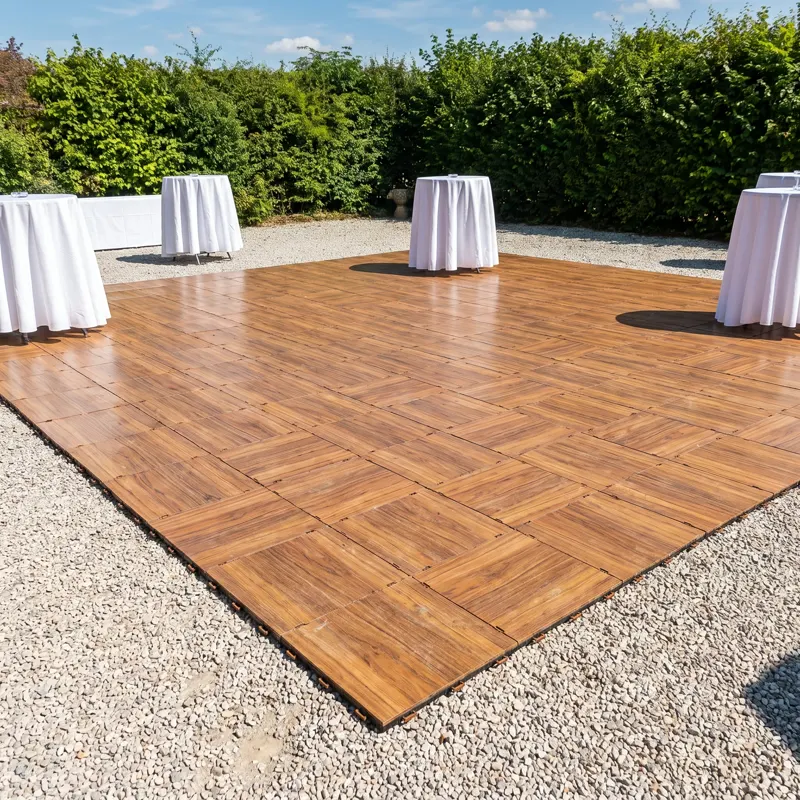 Piste de danse en dalles PVC finition teck posée directement sur le gravier d'une cour, avec tables de cocktail
